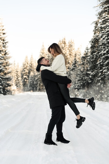 Young couple on the snow in winter in the park love and vacation concept  happy couple hugging and laughing outdoors in winter