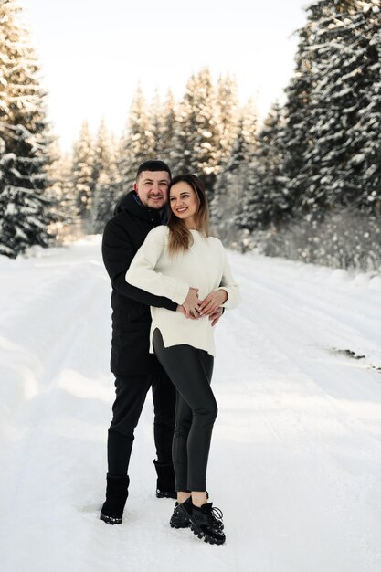 Young couple on the snow in winter in the park love and vacation concept  happy couple hugging and laughing outdoors in winter