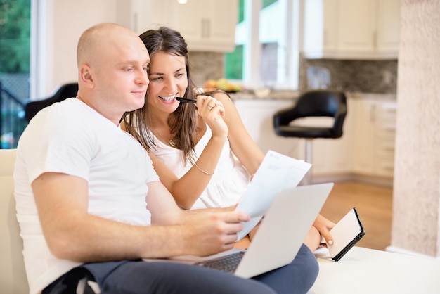 Young couple on the sofa with laptop and count the bill for payment. The concept of utilities, debt, people and credit.