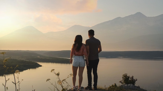 The young couple stand on mountain top on the beautiful river background