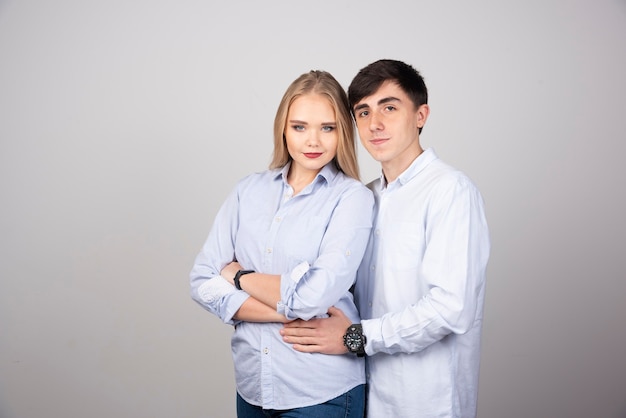 Young couple standing and looking against gray wall .