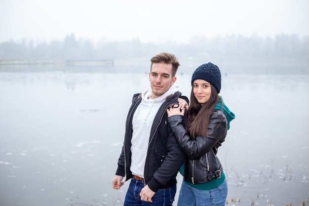 Young couple standing on the shore of Lake Gebart (Zalaegerszeg, Hungary) on a foggy winter day