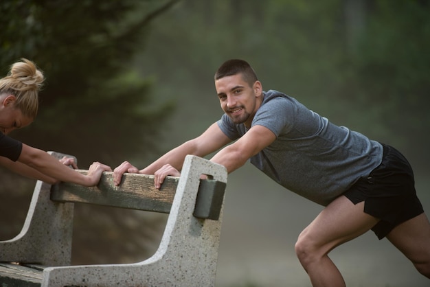 Photo young couple stretching before running in wooded forest area - training and exercising for trail run marathon endurance - fitness healthy lifestyle concept