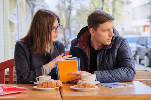 Young couple of students study in outdoor cafe