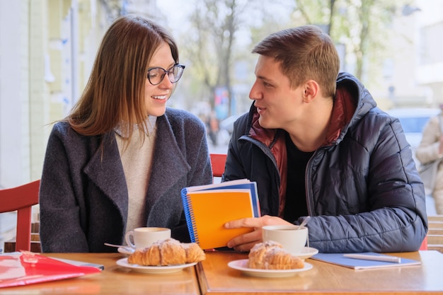 Young couple of students study in outdoor cafe