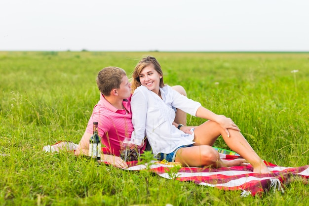 Young couple in summer meadow, man and woman having romantic picnic.