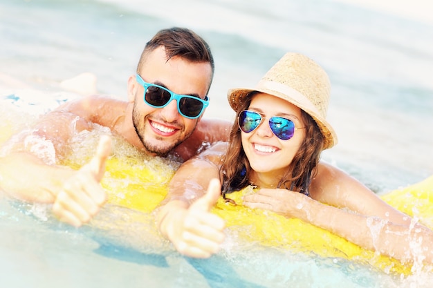 young couple swimming on a matress in the sea