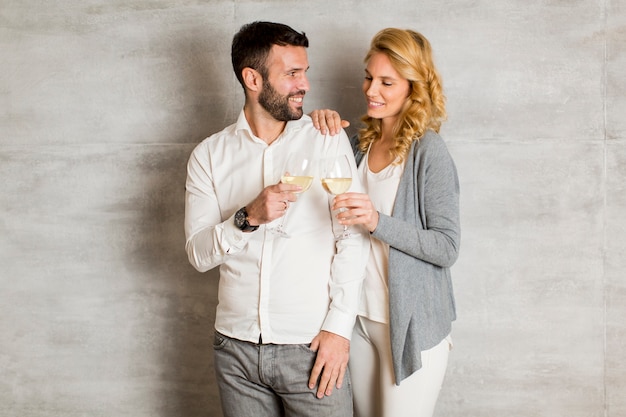 Young couple toasting with white wine by the wall