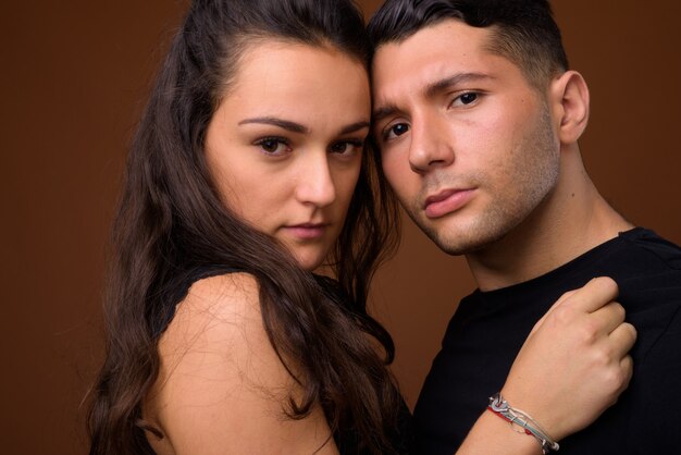 Young couple together and in love against brown wall