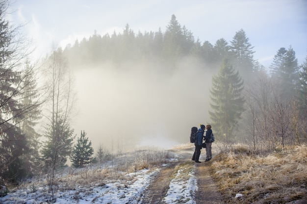 Young couple of tourists staying in the winter woods on the road and kiss