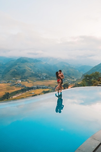 Young couple traveler relaxing at infinity pool with beautiful nature landscape mountains in Sapa Vietnam