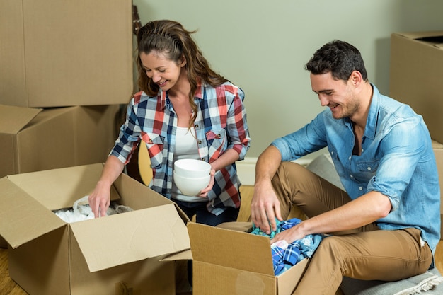 Young couple unpacking carton boxes in their new house