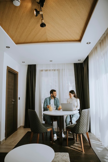 Young couple using laptop computer on the table in the living room and drinking orange juice