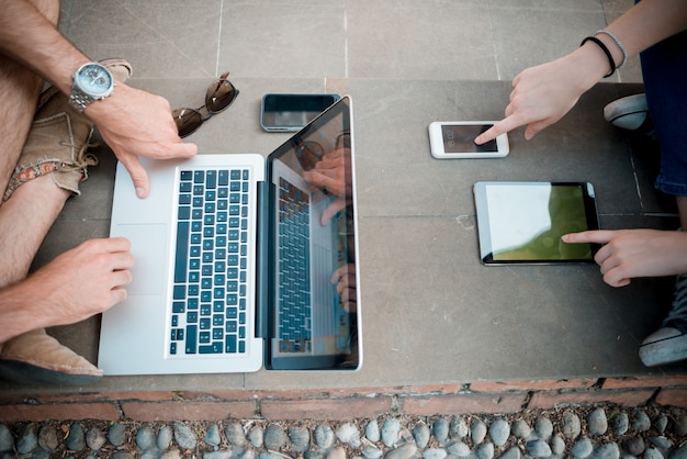 Photo young couple using technology multitasking smarpthone tablet and notebook