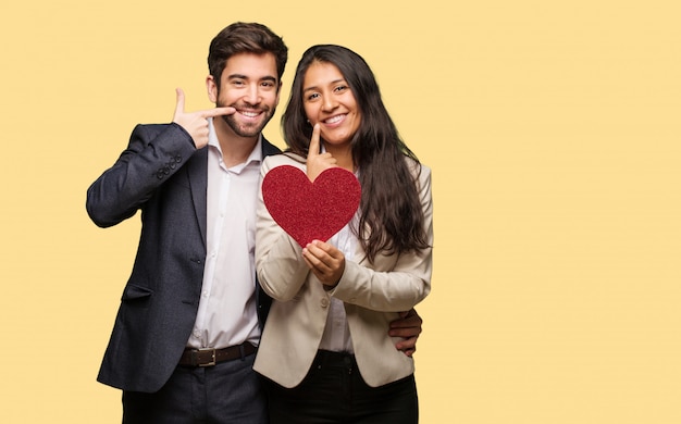 Young couple in valentines day smiles, pointing mouth