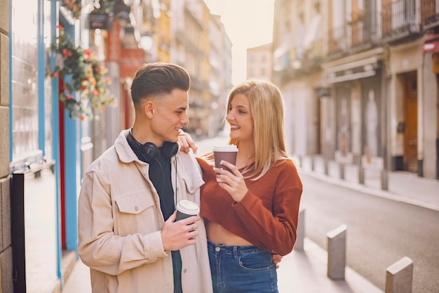 A young couple walk through the city and look at each other smiling