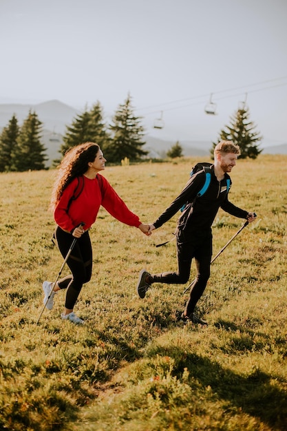 Young couple walking with backpack over green hills