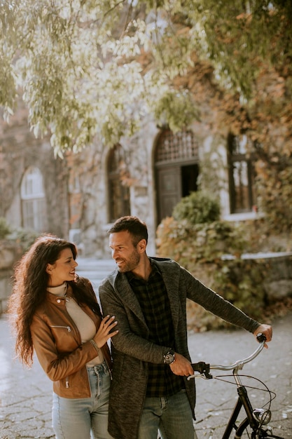 Young couple walking with bicycle in autumn park