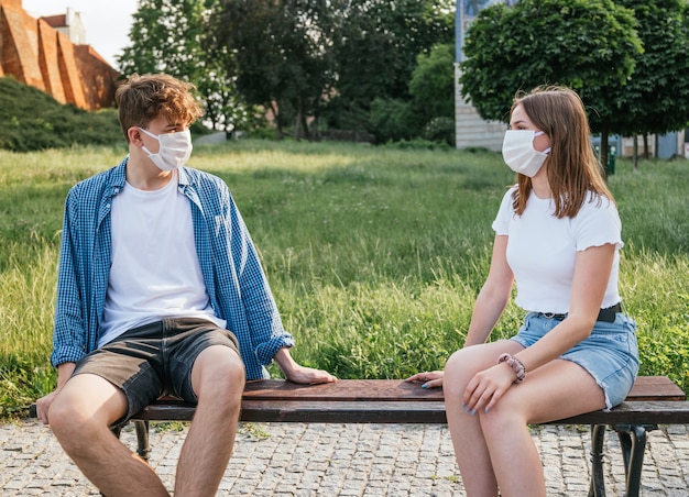 Young couple wearing masks and talking with social distance