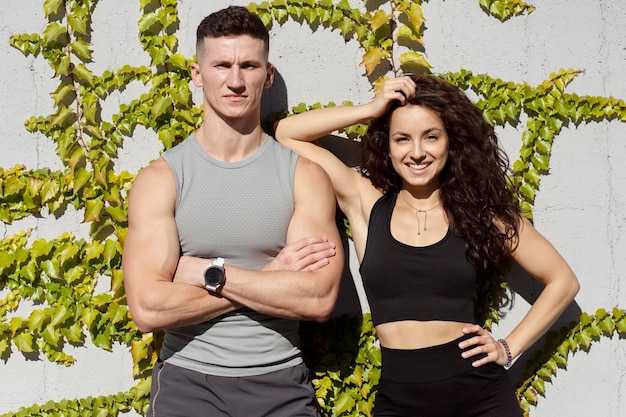 Young couple wearing sportswear standing at the street and posing after exercising