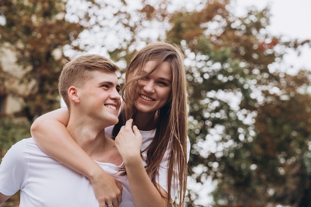 Young couple in white t-shirts and jeans walks the streets of the city and hold hands.