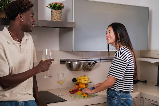 Young couple with diverse backgrounds chatting in the kitchen over a glass of wine Concept lifestyle relaxation love