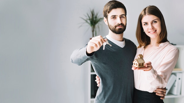 Young couple with keys and house