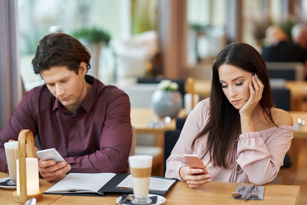 young Couple with smartphones In Cafe