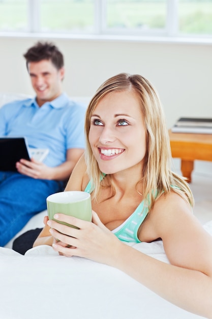 young couple. woman drinking tea when man using a laptop 