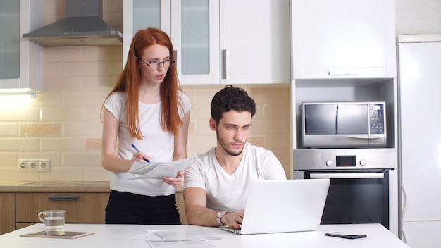 Young couple working on a laptop freelancers at home in the kitchen