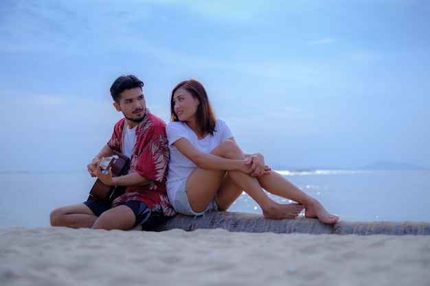 Young couples playing music and singing together on the beach