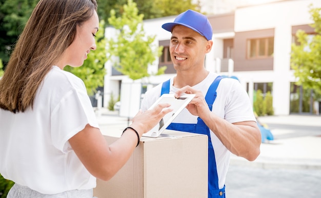 Young courier delivering goods to a young woman at home