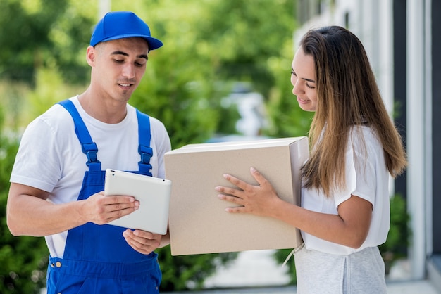 Young courier delivering goods to a young woman at home