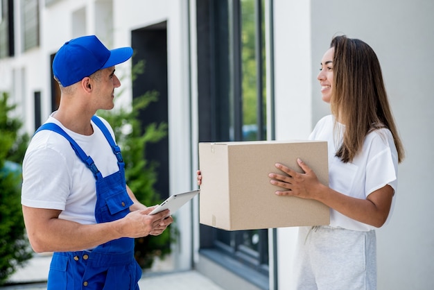 Young courier delivering goods to a young woman at home