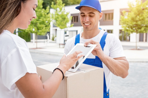 Young courier delivering goods to a young woman at home