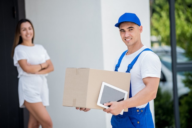 Young courier delivering goods to a young woman at home