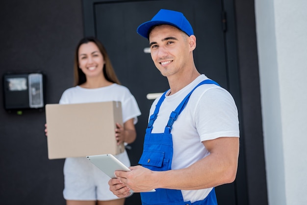 Young courier delivering goods to a young woman at home.