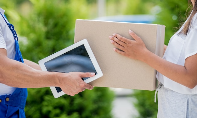 Young courier delivering goods to a young woman at home