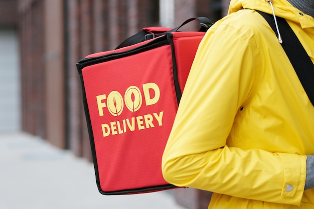 Young courier with big red backpack containing orders of clients