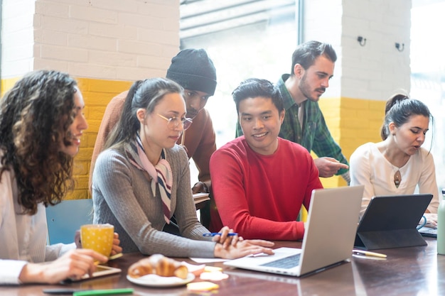 Young coworkers multiethnic team planning a new startup Happy people working on a new project in creative coworking office Marketing concept Bright filter with focus on asian man face