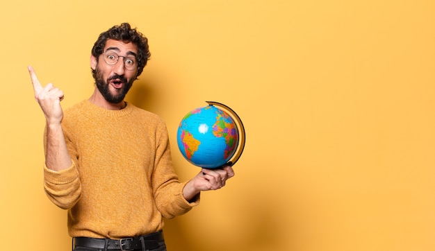 Young crazy bearded man holding a world globe map.