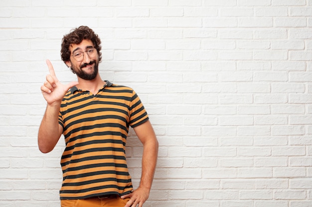 Young crazy or silly man gesturing and expressing emotions against brick wall background