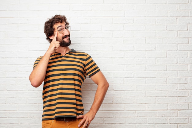 Young crazy or silly man gesturing and expressing emotions against brick wall background