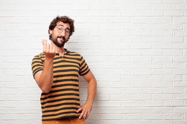 Young crazy or silly man gesturing and expressing emotions against brick wall background