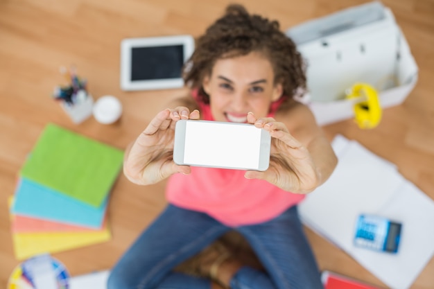 Young creative businesswoman showing her phone