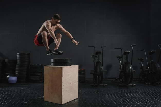 Young crossfit athlete doing box jump exercise at the gym