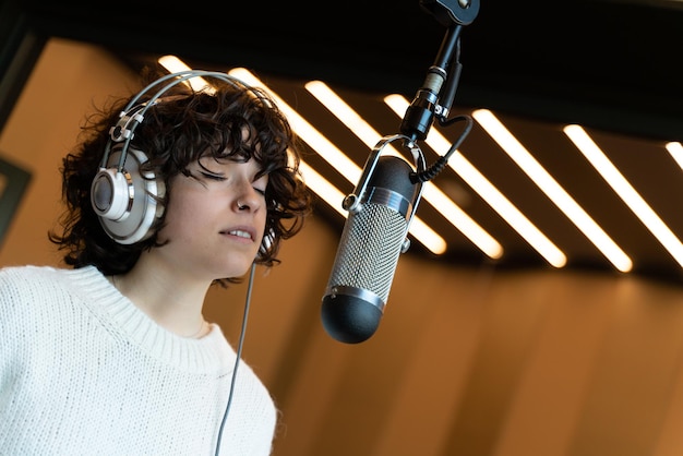 A young curly hair singer woman recording a song in a real studio