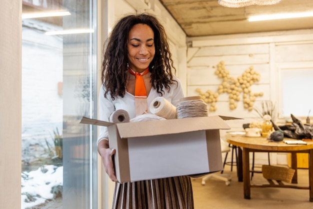 Young curly-haired woman with a cardboard in hands