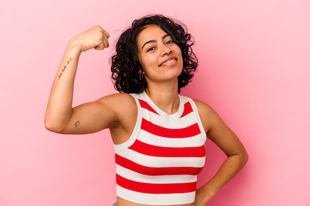 Young curly latin woman isolated on pink background cheering carefree and excited. Victory concept.