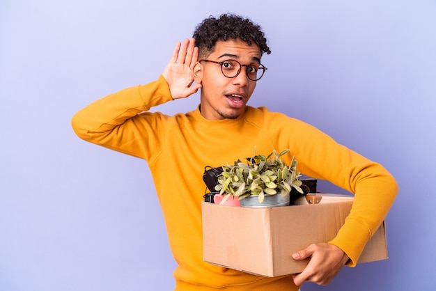 Young curly man isolated moving to a new home trying to listening a gossip